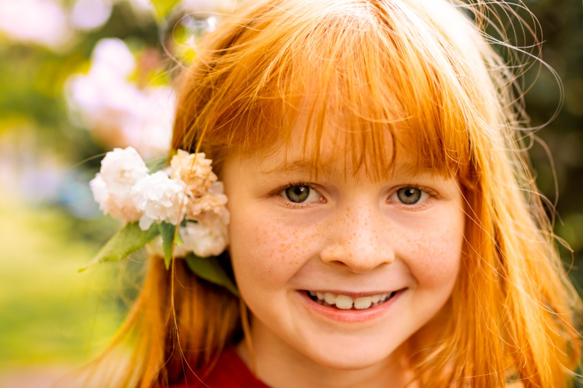 Ginger girl smiling has flowers in her hair