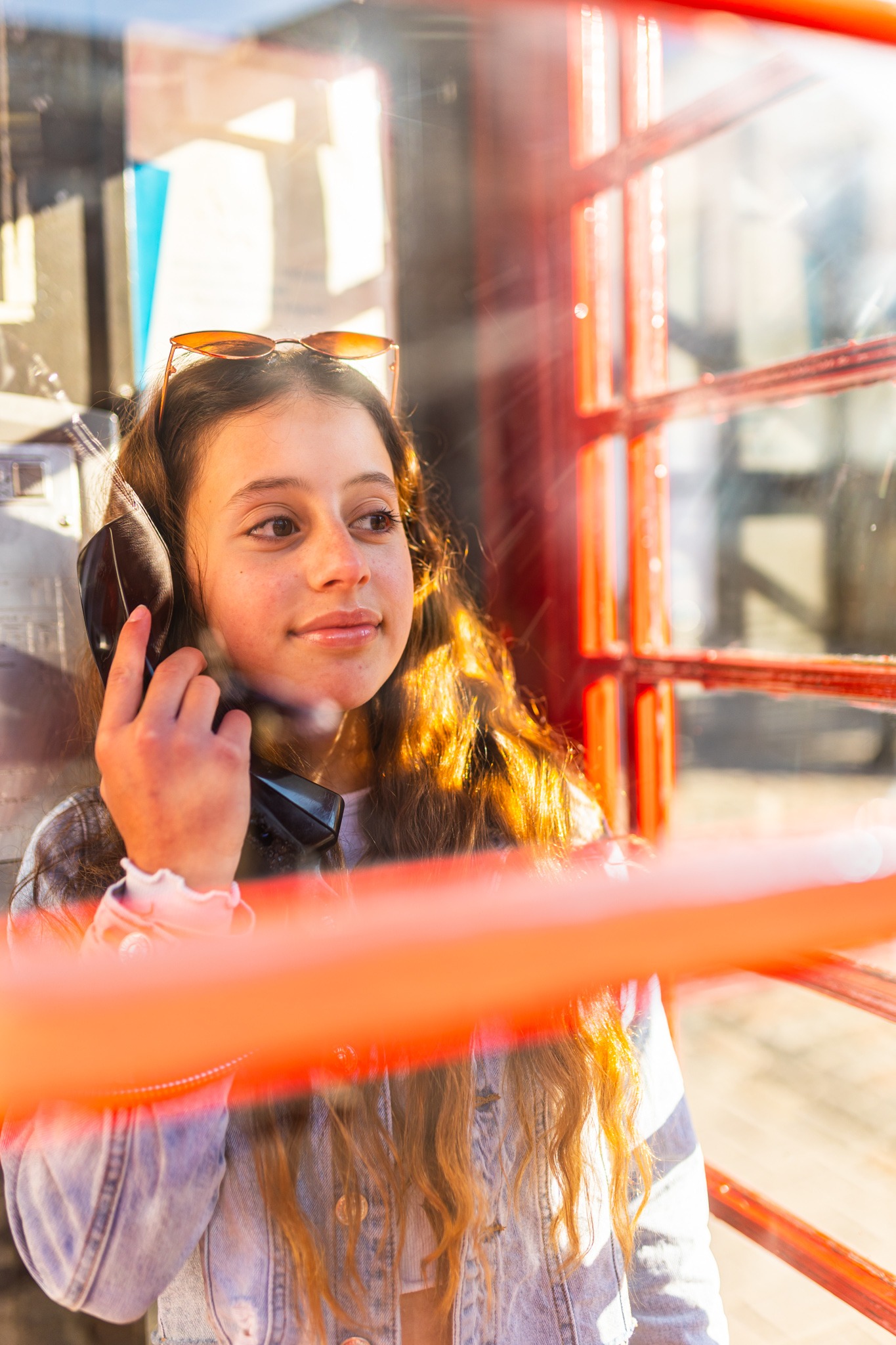 Young girl holding the phone in a red London phone booth